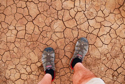 Low section of man standing on cracked field