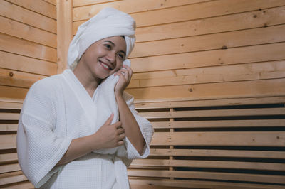 Smiling woman hair wrapped in towel while sitting at spa