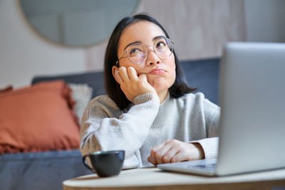 Portrait of young woman using laptop at home