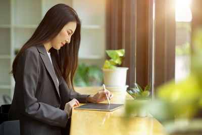 Woman holding mobile phone at table