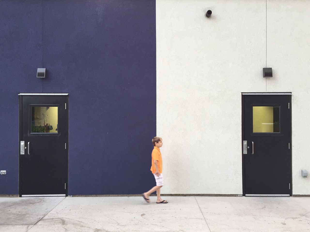 Full length of boy walking against building