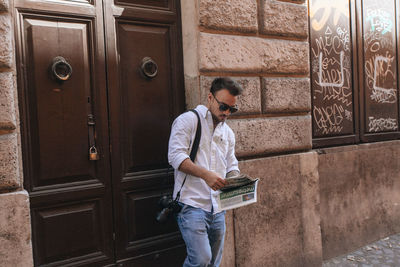 Full length of young man standing against door
