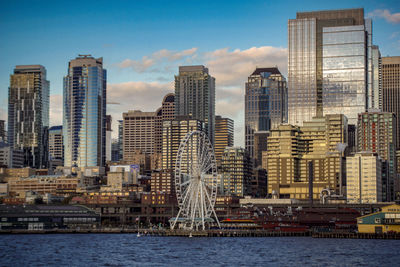 Modern buildings by river against sky in city