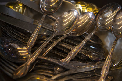 High angle view of steel spoons with forks and table knives