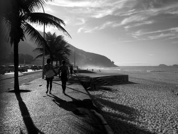 Rear view of people walking on footpath at beach