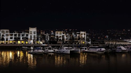 Boats moored at harbor in city at night