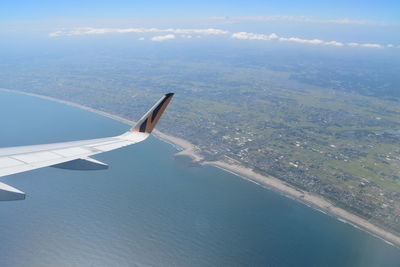 Aerial view of airplane flying over sea against sky