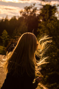 Woman with tousled hair on field during sunset