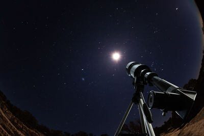 Low angle view of illuminated lighting equipment against sky at night