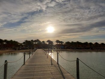 Pier over lake against sky during sunset