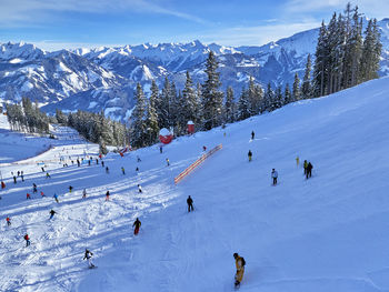 People skiing on snow covered mountains in sunny day