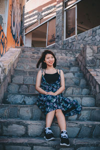 Portrait of smiling woman standing against staircase