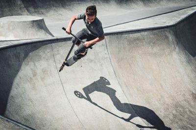 Full length of man riding push scooter at skateboard park