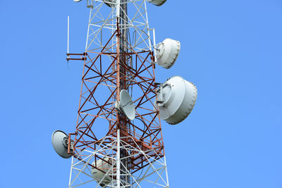 Low angle view of communications tower against clear blue sky