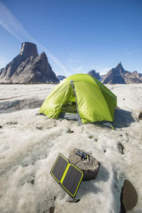 Solar panel charging with tent in background at remote campsite