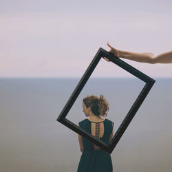 Woman standing by sea against sky