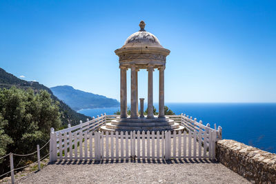 Gazebo by sea against clear blue sky