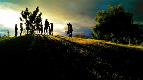 Silhouette people walking on field against sky