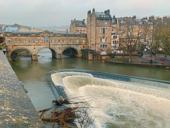 Arch bridge over river against buildings in city