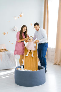 Young beautiful caucasian family playing with their one-year-old daughter in the children's room