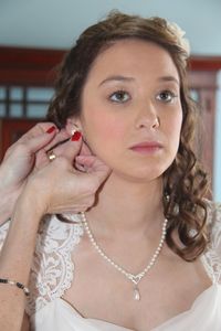 Cropped hands wearing earring to bride