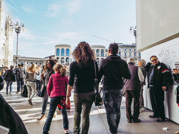 Rear view of people walking on street in city