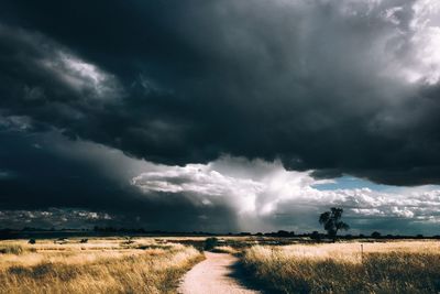 Scenic view of field against storm clouds