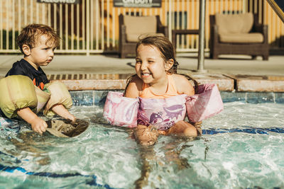 Full length of siblings in swimming pool