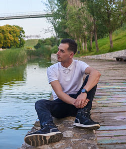 Portrait of young man sitting on lake