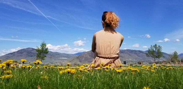 Rear view of woman sitting on flowering plants
