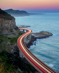 High angle view of light trails on bridge over sea during sunset
