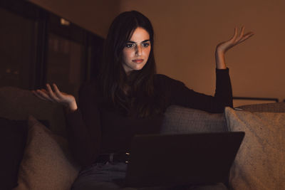 Young woman using laptop while sitting on sofa at home