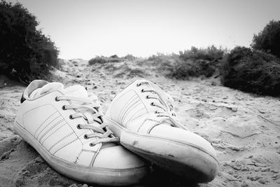 Close-up of shoes on sand at beach
