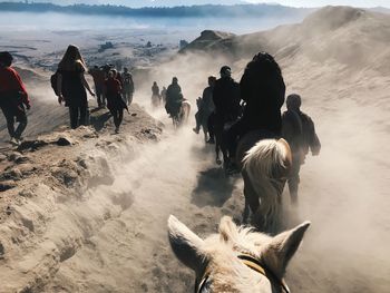 Rear view of people walking on dirt field