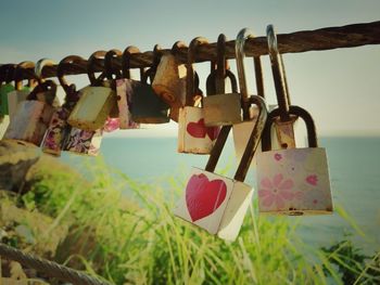 Close-up of padlocks hanging on railing against sky