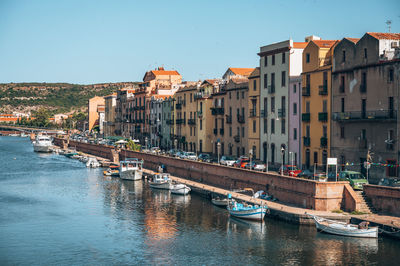 Boats in river by buildings against clear sky