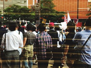 Crowd protesting on street seen through glass window with reflection