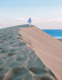 Rear view of man walking on beach