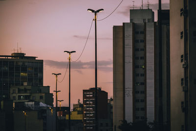 Illuminated city against sky at sunset