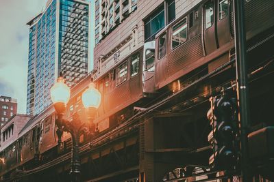 Low angle view of illuminated railroad tracks amidst buildings in city