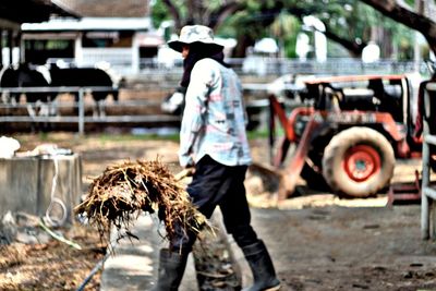 Side view full length of farmer holding fork with straw at farm