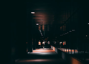 Rear view of people walking in illuminated building