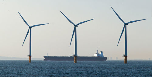 Wind turbines in sea against sky