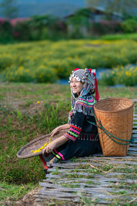 Woman sitting on wicker basket on field