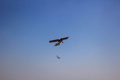 Low angle view of airplane flying against clear blue sky