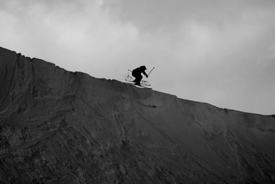 Low angle view of person jumping against sky