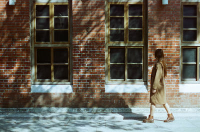 Side view of woman walking against building