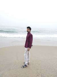 Full length of man standing on beach against clear sky