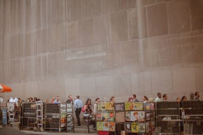 Side view of people walking against the wall