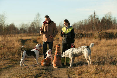 Couple with dogs standing on land